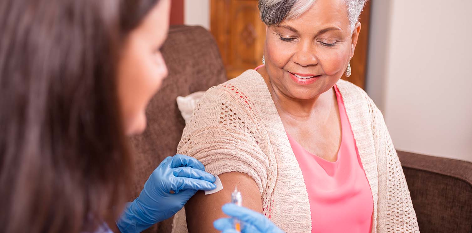 Older black lady getting a vaccine shot in her arm